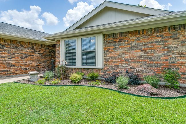 View of home's exterior with brick siding, a yard, and a shingled roof | Image 4