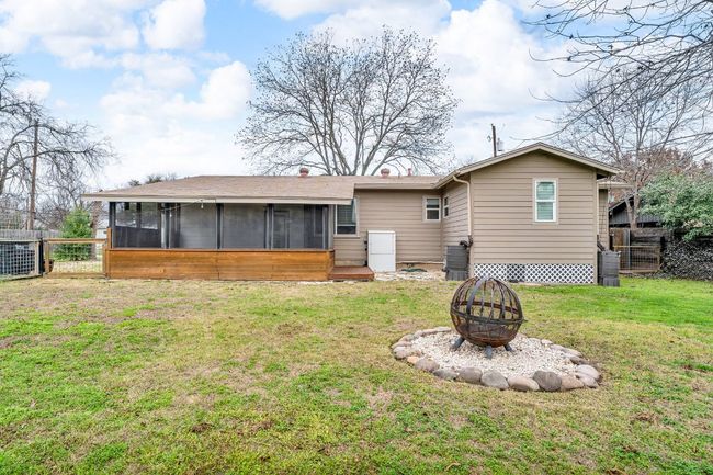 Rear view of house featuring a yard, a sunroom, fence, cooling unit, and a fire pit | Image 26