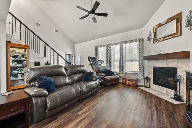 Living room featuring wood finished floors, ceiling fan, high vaulted ceiling, plenty of natural light, and a tile fireplace | Image 11