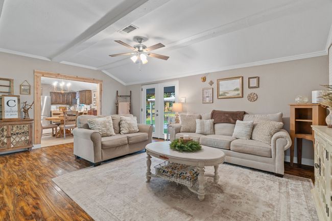 Living room with wood finished floors, french doors, a ceiling fan, and ornamental molding | Image 20