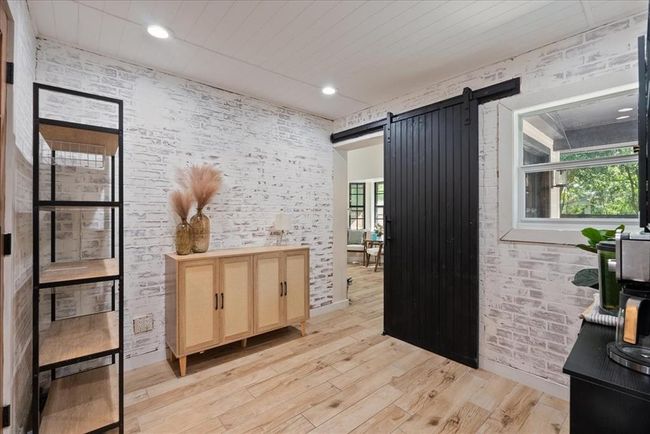 Chic flex space with whitewashed brick walls, wood floors, and a bold black sliding barn door. | Image 25
