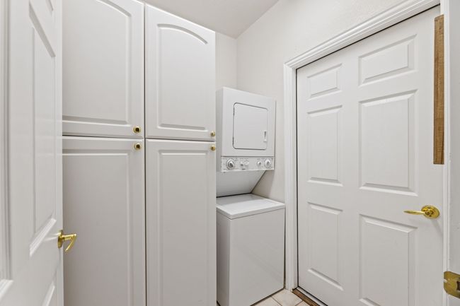 Laundry room featuring stacked washer and clothes dryer and cabinet space | Image 35