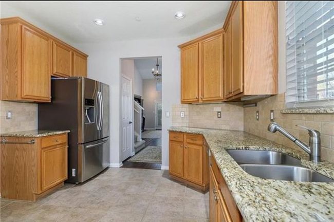 Kitchen with stainless steel refrigerator with ice dispenser, sink, tasteful backsplash, and light tile floors | Image 7