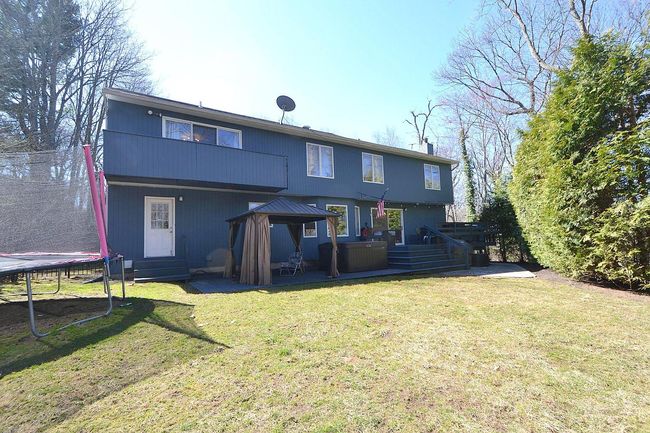 Rear view of property featuring a trampoline, a jacuzzi, a gazebo, entry steps, and a lawn | Image 22