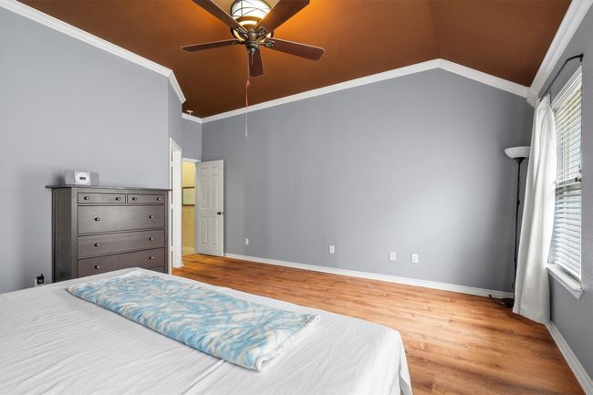 Bedroom featuring wood finished floors, vaulted ceiling, ceiling fan, and crown molding | Image 25
