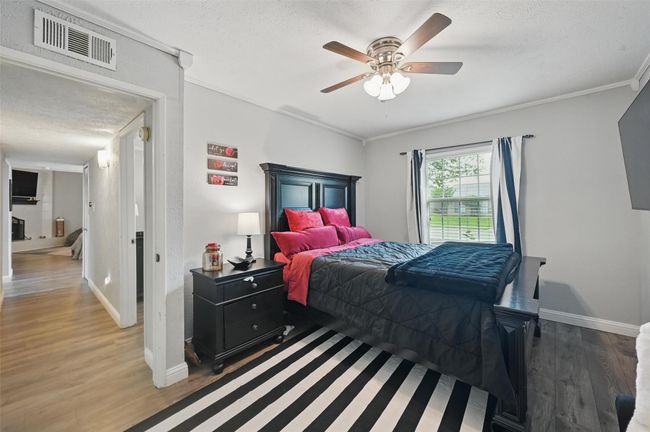 Bedroom featuring wood finished floors, a textured ceiling, ornamental molding, and a ceiling fan | Image 21