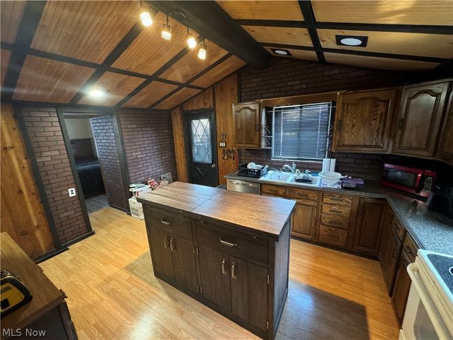 Kitchen featuring lofted ceiling with beams, wood counters, light wood-type flooring, brick wall, and appliances with stainless steel finishes | Image 11