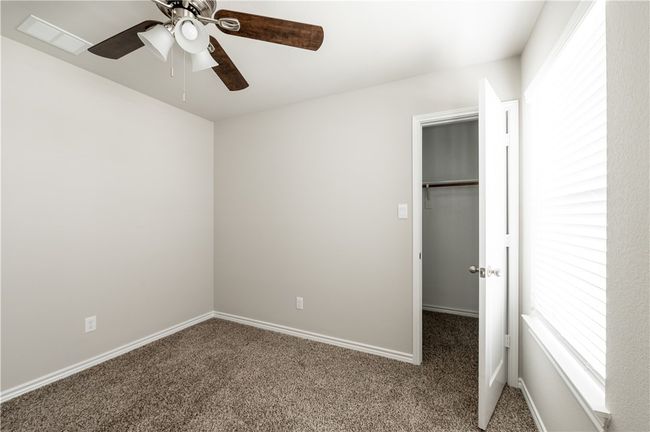 Unfurnished bedroom featuring a spacious closet, visible vents, ceiling fan, baseboards, and carpet floors | Image 19