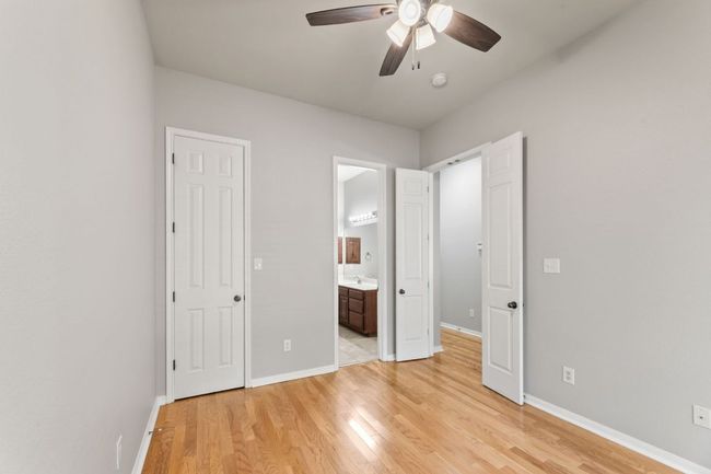 Unfurnished bedroom featuring light wood finished floors, ensuite bath, and ceiling fan | Image 20