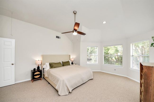 The primary bedroom boasts high ceilings and an open layout that offers plenty of space to display your favorite furniture and decor without sacrificing comfort or function. This generous room invites you to create a personalized retreat—whether that’s a cozy reading corner by the windows or an elegant arrangement that enhances its warm, inviting ambiance. | Image 27