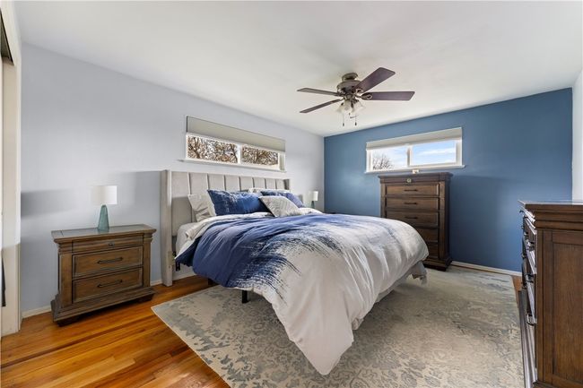 This lovely primary bedroom is complete with hardwood floors, soft blue tones, a ceiling fan, and a nice size closet. | Image 12