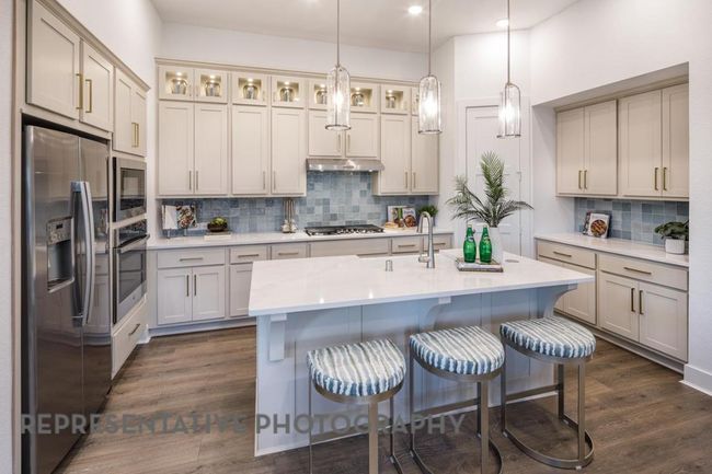 Kitchen featuring appliances with stainless steel finishes, tasteful backsplash, dark wood-style floors, light countertops, and a breakfast bar area | Image 5
