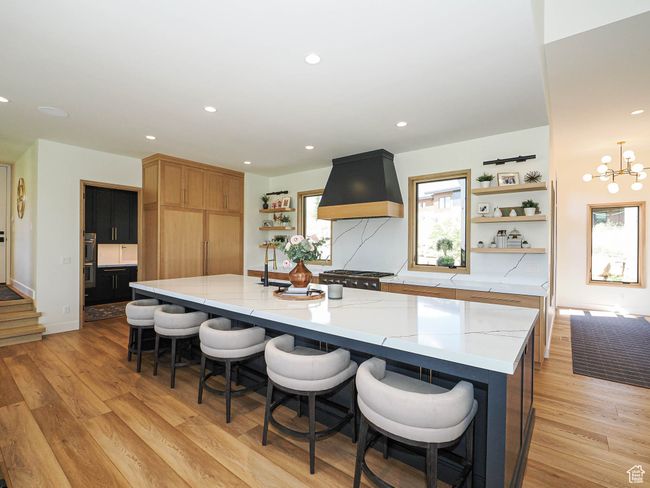 Kitchen with open shelves, custom exhaust hood, light wood-style floors, a large island, and recessed lighting | Image 31