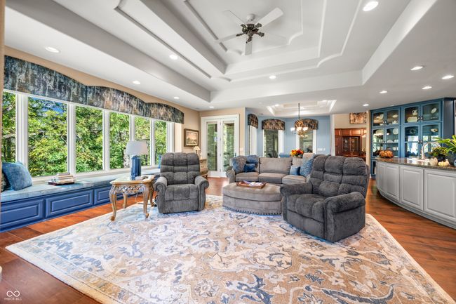 living room featuring dark wood-style floors, recessed lighting, a raised ceiling, and ceiling fan with notable chandelier | Image 21