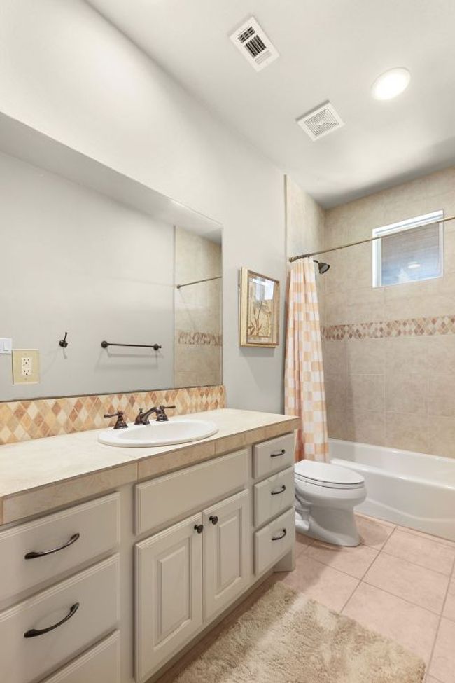 Full bathroom upstairs with toilet, vanity, tile patterned floors, shower / tub combo, and decorative backsplash | Image 25