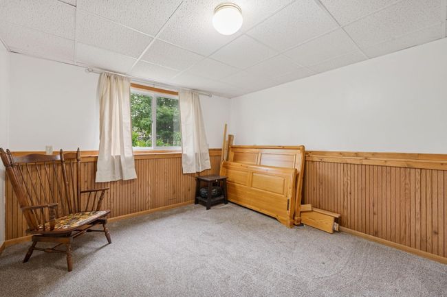 The third and final bedroom is located in the lower level, adorned with wood on the lower portion of walls. | Image 23