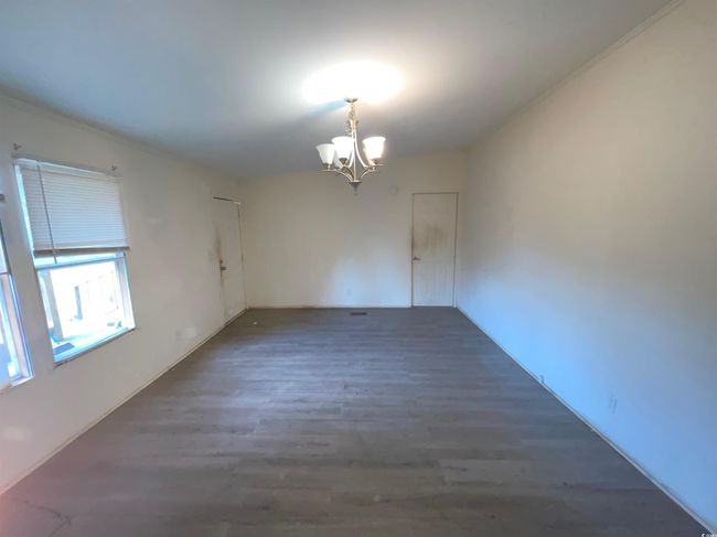 Spare room with a chandelier and wood finished floors | Image 14