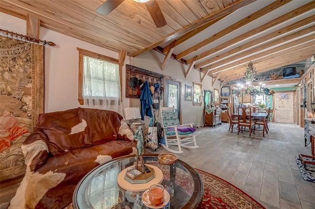 Stepping through the front door, you're met with an open layout accented by wood-paneled ceilings, exposed beams, and earthy tile floors. The seamless flow of this space invites conversation and comfort in equal measure. | Image 6