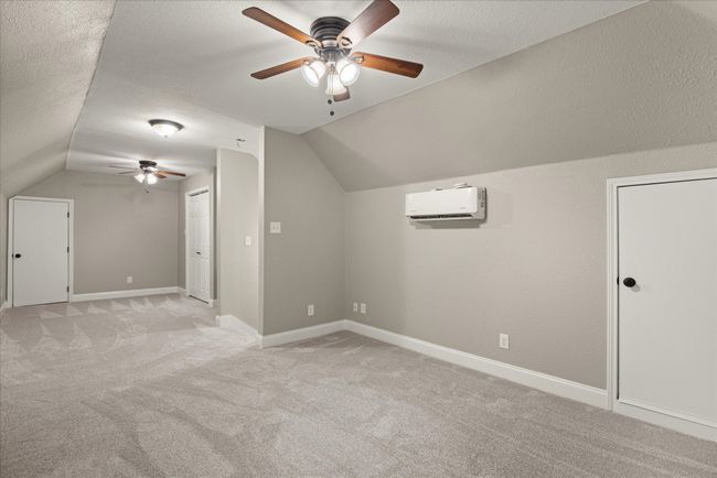 Bonus room with ceiling fan, a wall unit AC, vaulted ceiling, light colored carpet, and a textured ceiling | Image 13