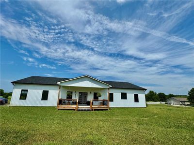 Rear view of house with a yard and a wooden deck | Image 1