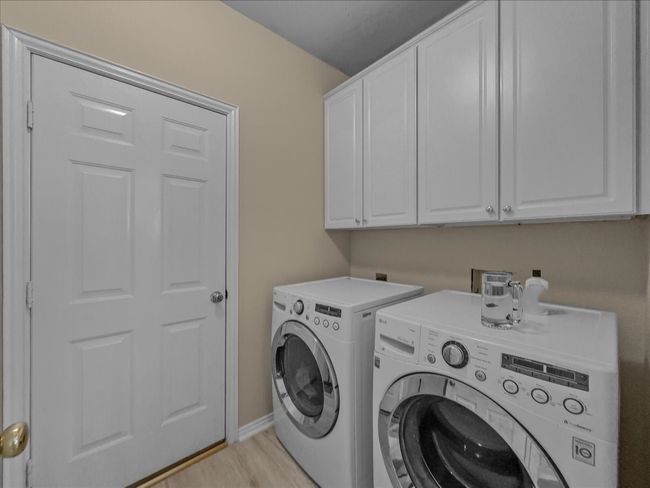 Laundry room with cabinet space, independent washer and dryer, and light wood-style floors | Image 15