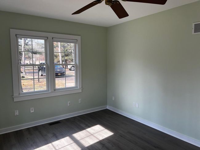 Unfurnished room featuring dark wood-style flooring, a ceiling fan, visible vents, and baseboards | Image 6