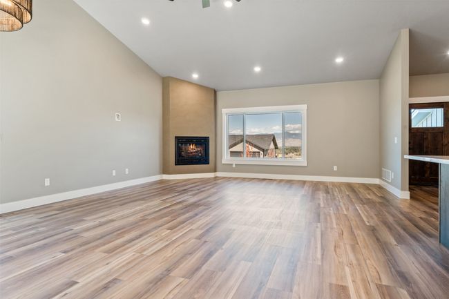 Unfurnished living room featuring wood finished floors, a fireplace, baseboards, and recessed lighting | Image 12