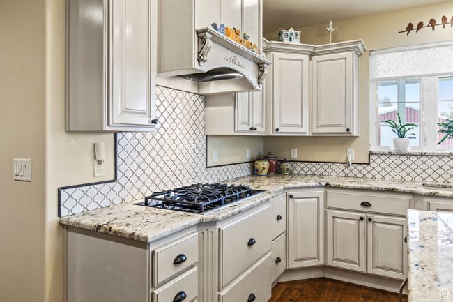 Kitchen featuring white cabinets, light stone counters, black gas cooktop, and tasteful backsplash | Image 28