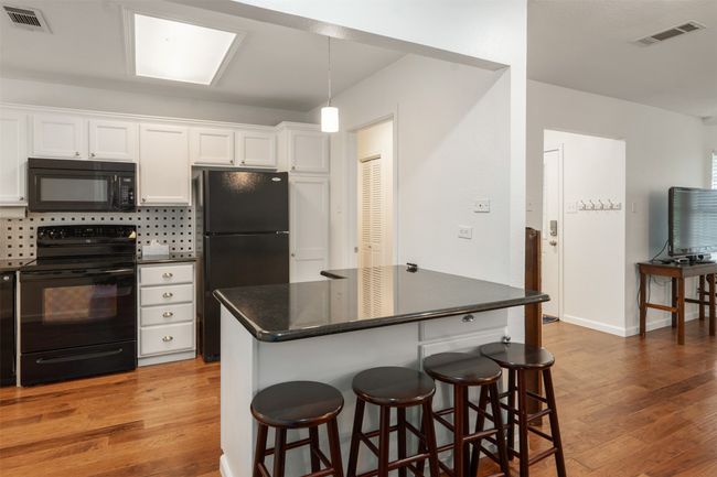 Kitchen with black appliances also features a eating bar for extra seating. | Image 12