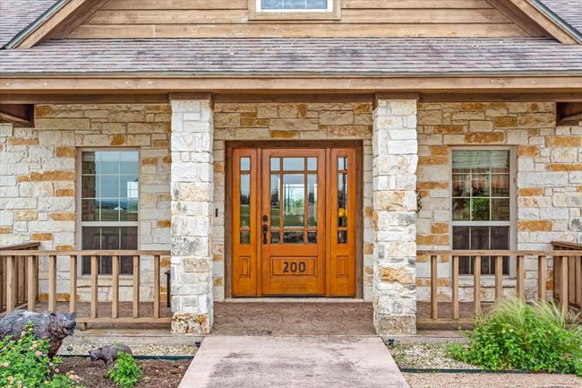 Entrance to property featuring stone siding and roof with shingles | Image 7