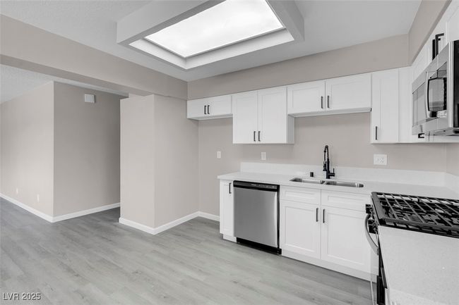 Kitchen with light wood finished floors, light countertops, a sink, and appliances with stainless steel finishes | Image 14