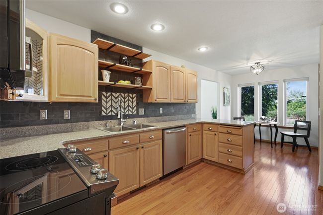 Beautiful wood cabinetry with hard surface countertops and backsplash. All appliances stay with home. | Image 16