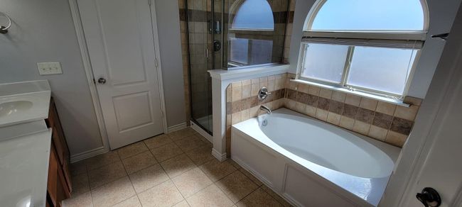 Full bathroom with a bath, a stall shower, vanity, and light tile patterned floors | Image 16