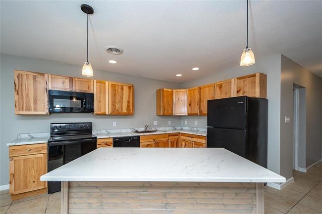 Kitchen featuring visible vents, black appliances, pendant lighting, a sink, and light tile patterned floors | Image 14