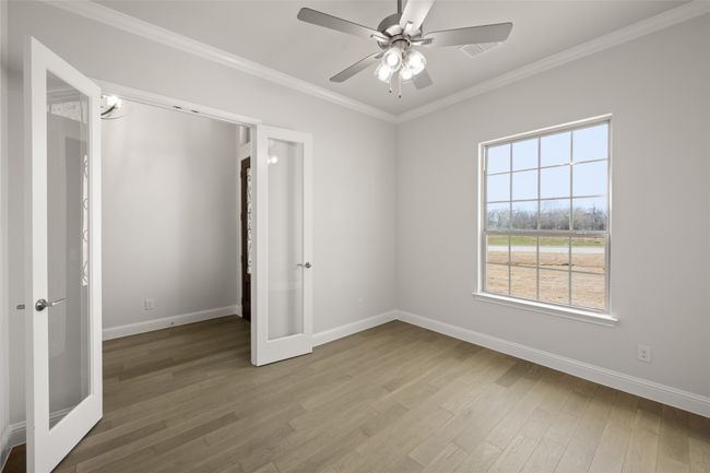Spare room with french doors, wood finished floors, baseboards, ornamental molding, and a ceiling fan | Image 12