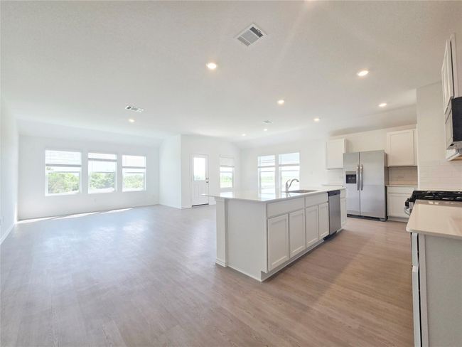 Kitchen featuring appliances with stainless steel finishes, a sink, open floor plan, a center island with sink, and light wood-type flooring | Image 25