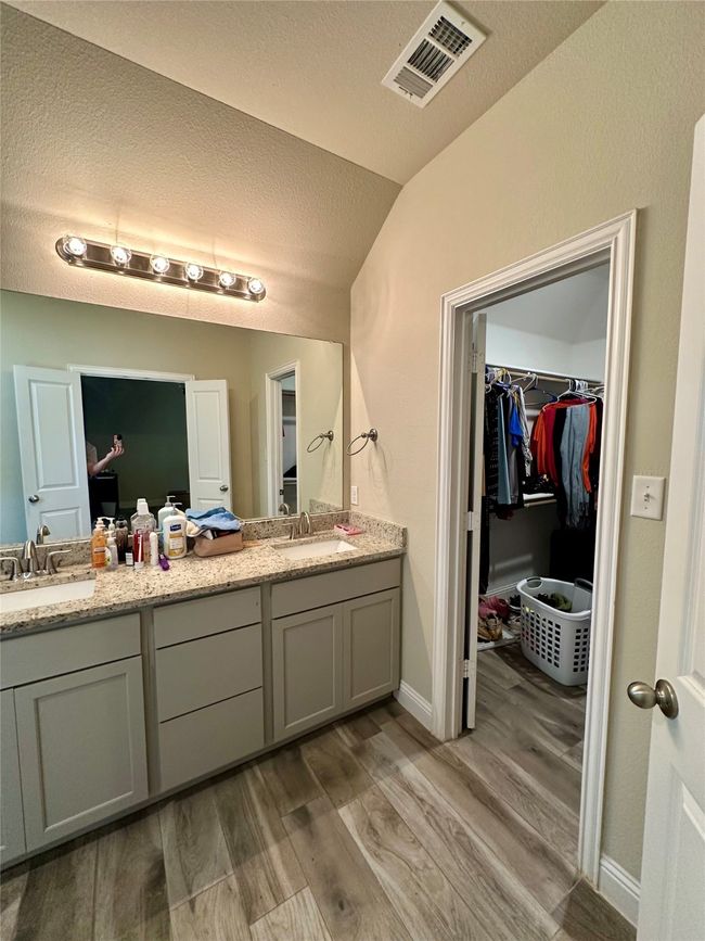 Full bathroom featuring double vanity, lofted ceiling, wood finished floors, a walk in closet, and a textured ceiling | Image 34