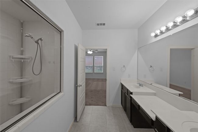Bathroom with vanity, tile patterned floors, a tile shower, and ceiling fan | Image 20
