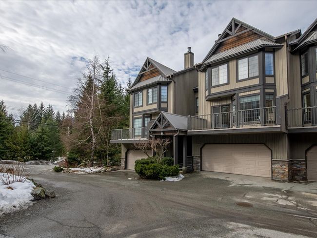 View of property with a garage, stone siding, a chimney, and aphalt driveway | Image 32