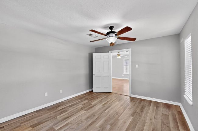 Unfurnished bedroom with wood finished floors, ceiling fan, and a textured ceiling | Image 5