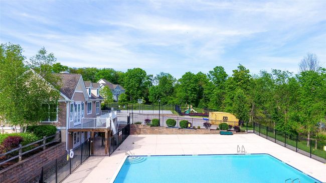 Community pool featuring fence, a patio, and view of wooded area | Image 34