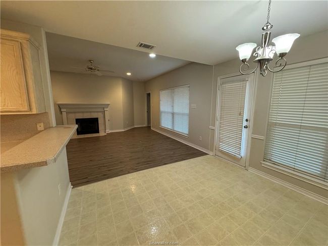 Unfurnished living room featuring light flooring, ceiling fan, a chandelier, a tile fireplace, and recessed lighting | Image 4
