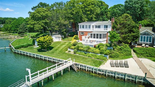 Rear view of property with a water view, a chimney, brick siding, a lawn, and an outdoor living space | Image 13