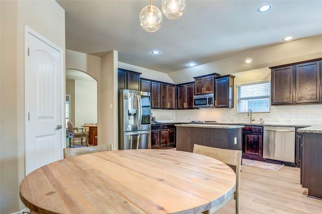 Kitchen featuring backsplash, dark brown cabinets, appliances with stainless steel finishes, light wood finished floors, and a sink | Image 19