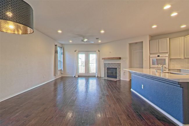 Unfurnished living room with dark wood-type flooring, a ceiling fan, recessed lighting, and a fireplace | Image 8