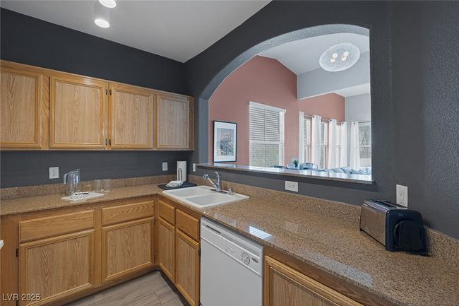 Kitchen with light brown cabinets, light wood-type flooring, arched walkways, a sink, and dishwasher | Image 8