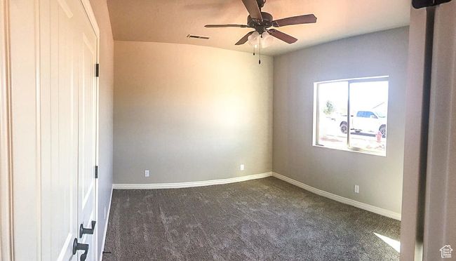 Empty room featuring baseboards, dark colored carpet, visible vents, and a ceiling fan | Image 13