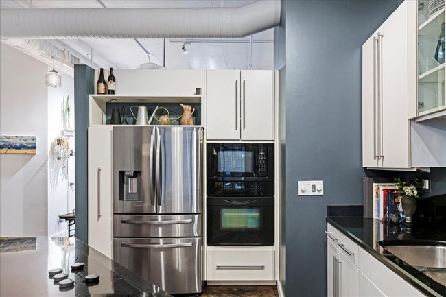 Kitchen with black appliances, white cabinetry, and glass insert cabinets | Image 5