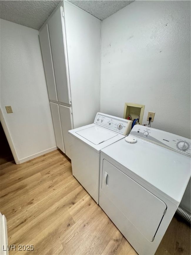 Laundry room with light wood-style flooring, washing machine and dryer, and a textured ceiling | Image 32