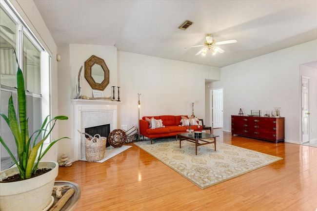 Bright, spacious living room with wood flooring, a cozy fireplace, and large windows. | Image 8